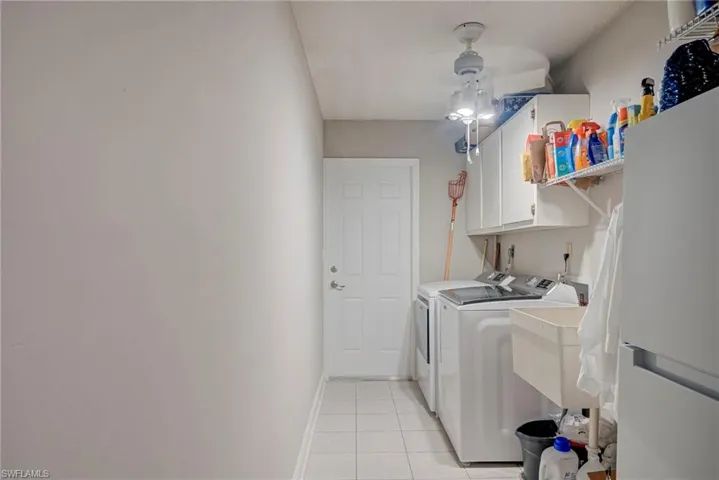 Washroom featuring cabinet space, light tile patterned floors, and washer and dryer