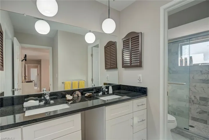 Full bathroom featuring double vanity, a shower stall, and marble finish flooring