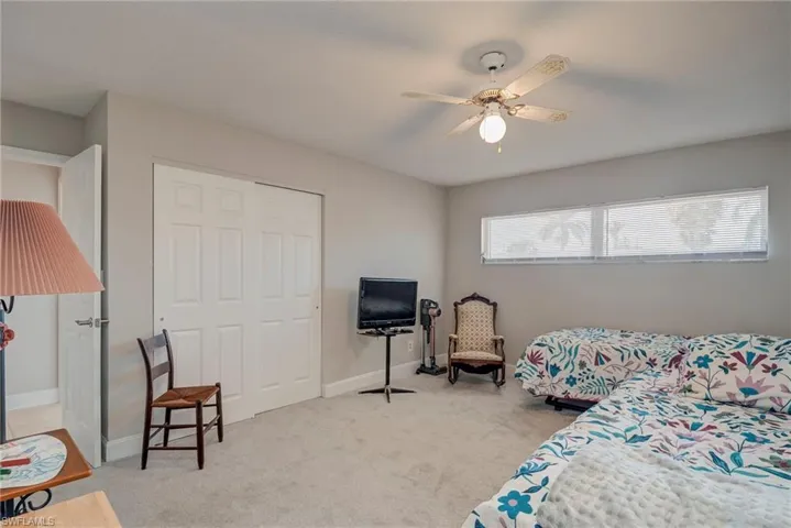 Bedroom with light carpet, a ceiling fan, and a closet