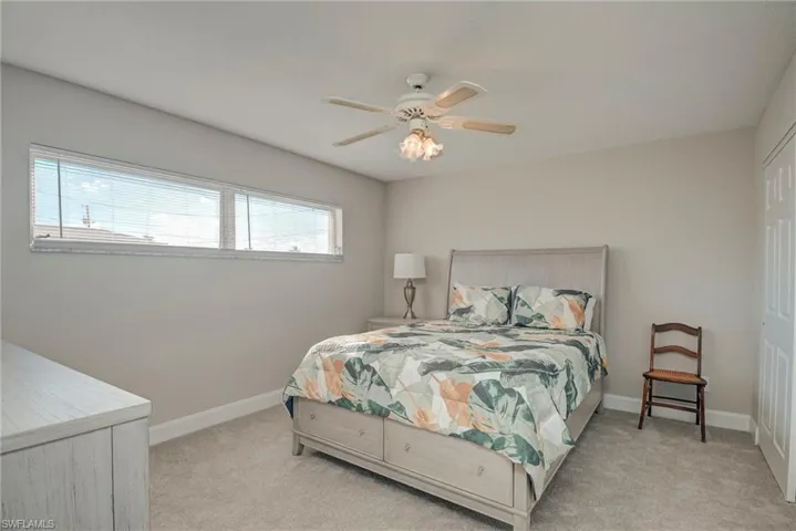 Bedroom with light colored carpet, ceiling fan, and a closet