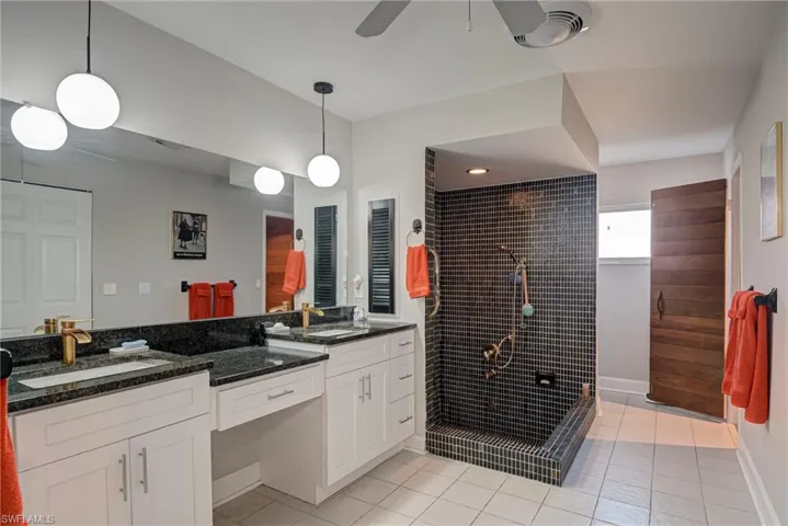 Bathroom with a walk in shower, light tile patterned floors, double vanity, and a ceiling fan