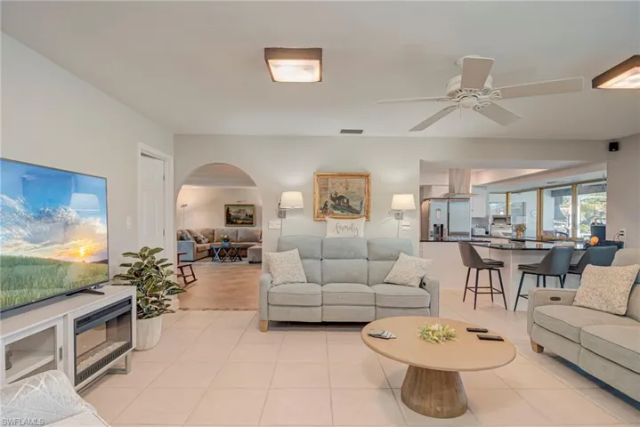Living room with arched walkways, light tile patterned floors, and ceiling fan