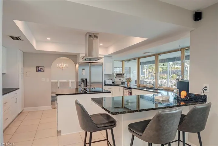 Kitchen with a raised ceiling, a peninsula, a kitchen bar, and recessed lighting