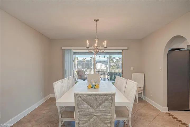 Dining space featuring a chandelier, arched walkways, and light tile patterned flooring