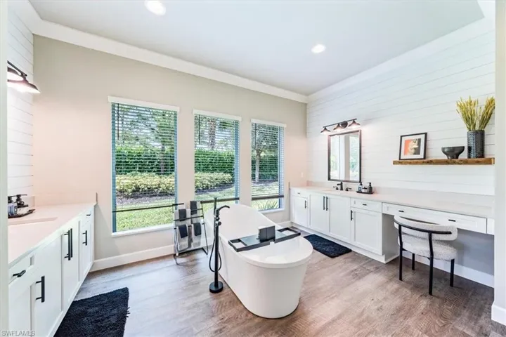 Bathroom featuring vanity, a bath, hardwood / wood-style floors, and crown molding