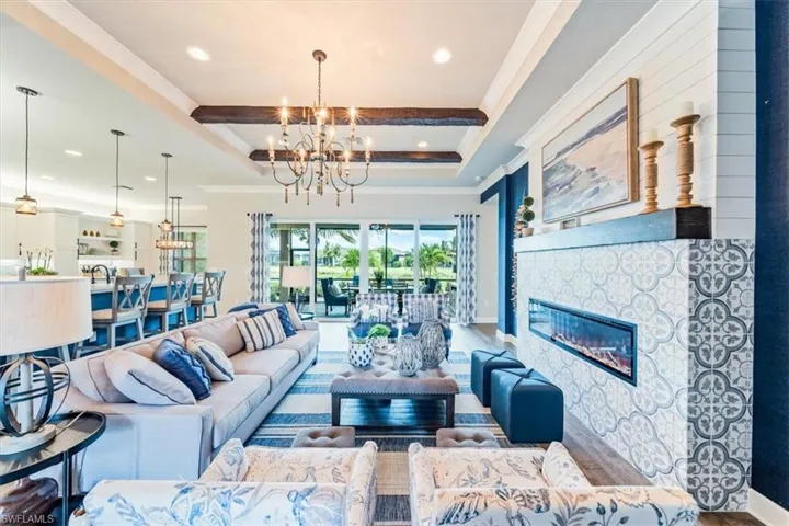 Living room featuring wood-type flooring, an inviting chandelier, crown molding, and beam ceiling