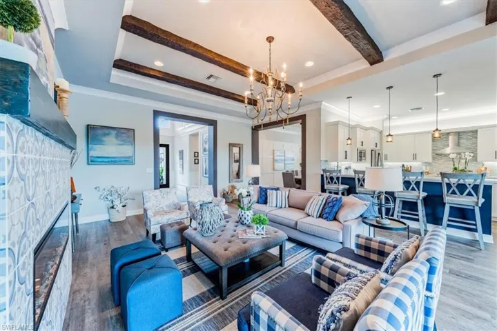 Living room with an inviting chandelier, a fireplace, a tray ceiling, and hardwood / wood-style flooring