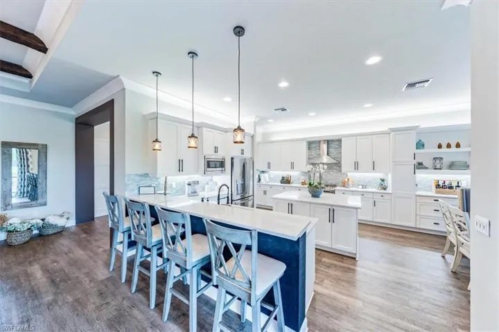 Kitchen with a kitchen bar, pendant lighting, stainless steel appliances, and hardwood / wood-style flooring