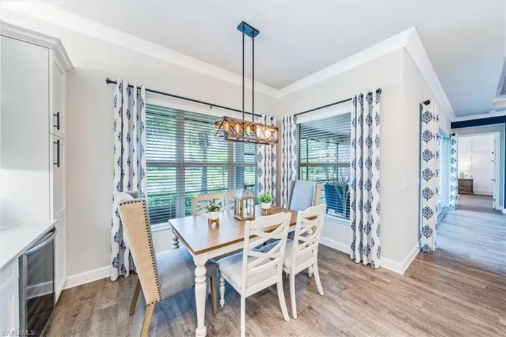 Dining room featuring light wood-type flooring, ornamental molding, beverage cooler, and a notable chandelier