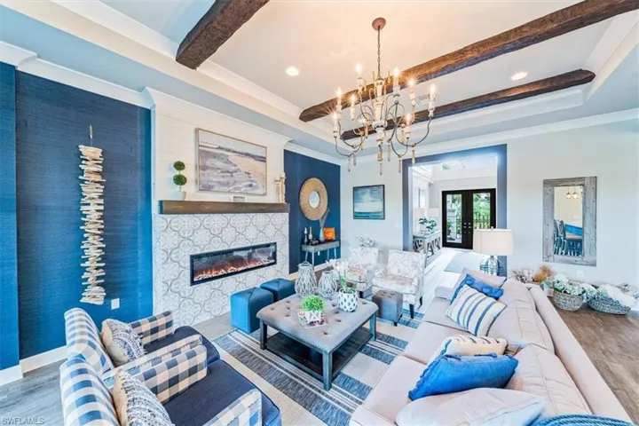 Living room featuring a notable chandelier, beam ceiling, hardwood / wood-style flooring, and french doors