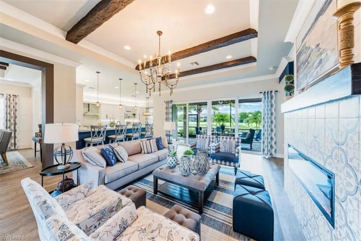 Living room with ornamental molding, an inviting chandelier, light wood-type flooring, and beam ceiling