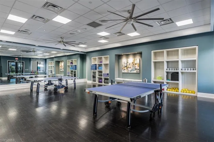 Rec room featuring a drop ceiling, hardwood / wood-style floors, and ceiling fan