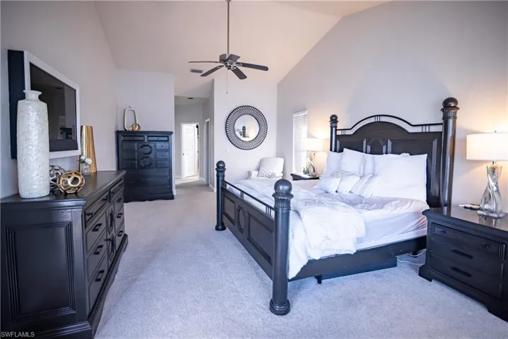 Bedroom with lofted ceiling, light carpet, and ceiling fan