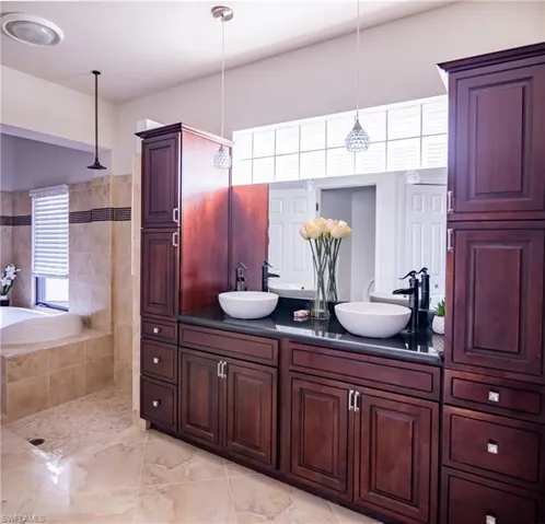 Full bathroom featuring double vanity, walk in shower, and a relaxing tiled tub