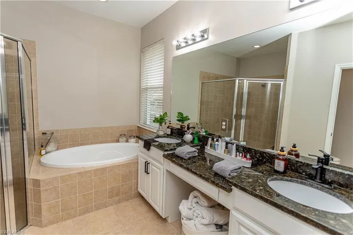 Full bathroom with double vanity, light tile patterned flooring, a bath, and a shower stall