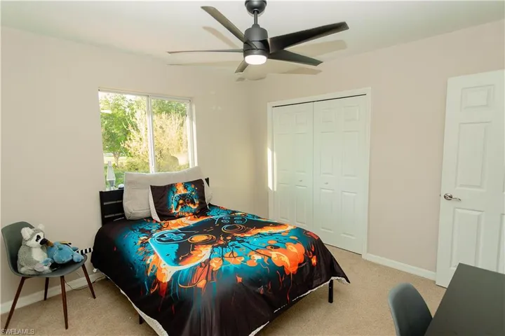 Bedroom with light colored carpet, a ceiling fan, and a closet