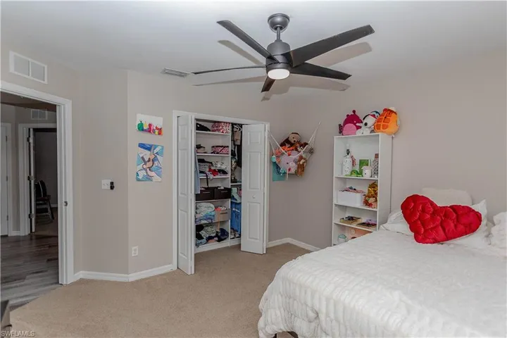 Bedroom featuring light colored carpet, a ceiling fan, and a closet