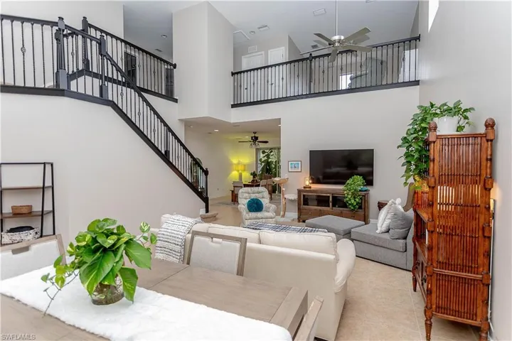 Living room featuring ceiling fan, a high ceiling, and tile patterned floors