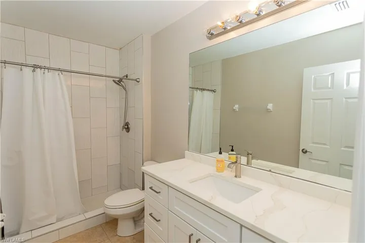 Full bathroom featuring a stall shower, vanity, and light tile patterned flooring