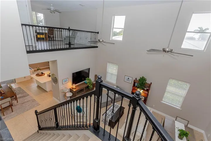 Stairs with ceiling fan, a high ceiling, and tile patterned flooring
