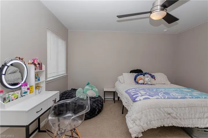 Bedroom with light colored carpet and a ceiling fan