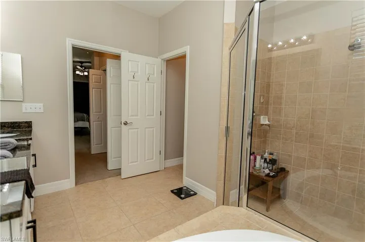 Full bath with double vanity, a stall shower, light tile patterned floors, and connected bathroom