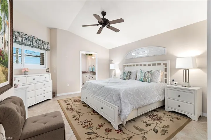 Bedroom with light tile patterned flooring, lofted ceiling, baseboards, visible vents, and ceiling fan
