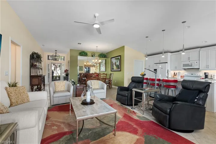 Living room with light tile patterned floors and ceiling fan with notable chandelier