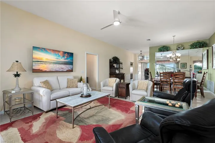 Living room featuring visible vents and ceiling fan with notable chandelier