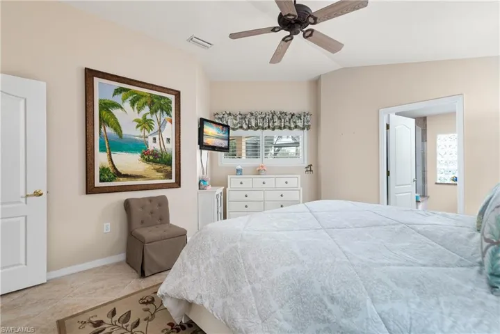 Bedroom with baseboards, light tile patterned floors, vaulted ceiling, and a ceiling fan