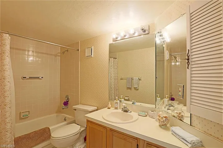 Full bathroom with toilet, vanity, shower / tub combo with curtain, and a textured ceiling