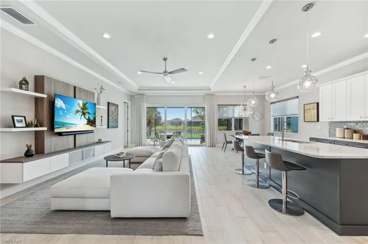 Living room featuring visible vents, recessed lighting, ceiling fan, ornamental molding, and a raised ceiling