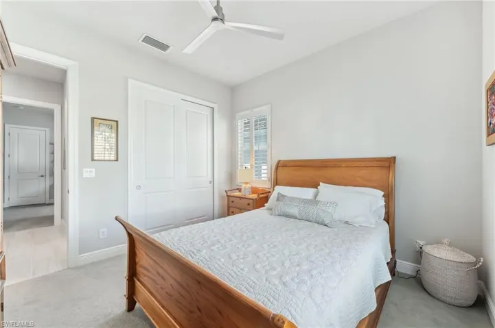 Carpeted bedroom featuring a ceiling fan, visible vents, baseboards, and a closet