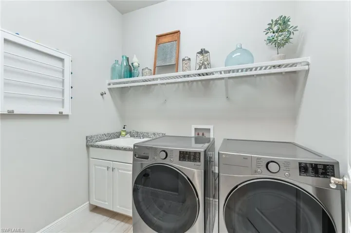 Laundry area with a sink, baseboards, cabinet space, and washing machine and clothes dryer