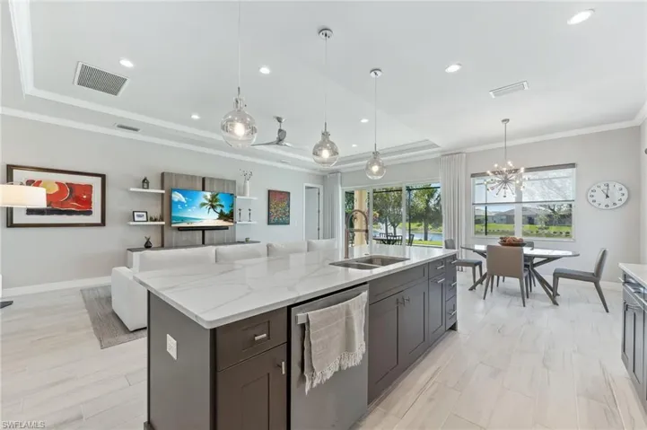 Kitchen with visible vents, a tray ceiling, ornamental molding, a sink, and stainless steel dishwasher