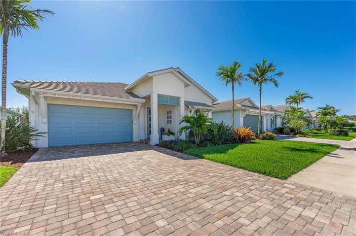 View of front of home featuring stucco siding, a front lawn, a tile roof, decorative driveway, and a garage