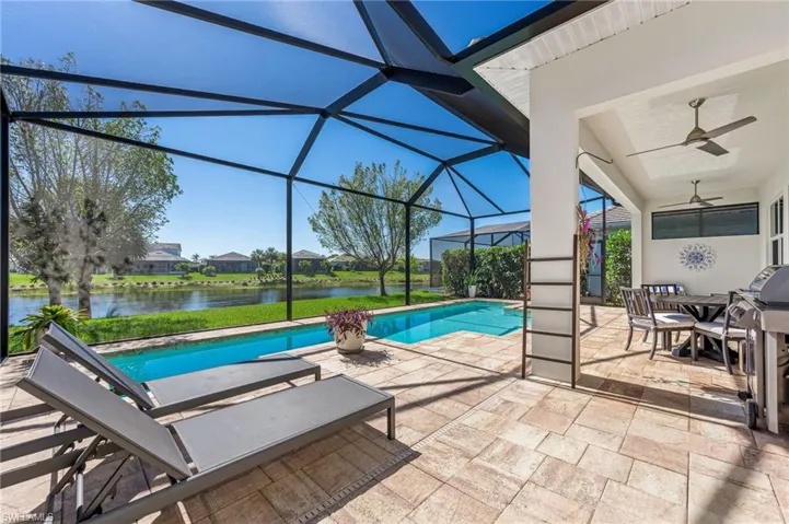 Pool featuring a patio, a lanai, a ceiling fan, and a water view