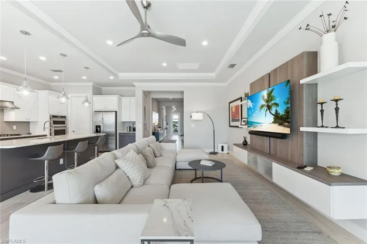 Living room featuring visible vents, ornamental molding, recessed lighting, a raised ceiling, and a ceiling fan