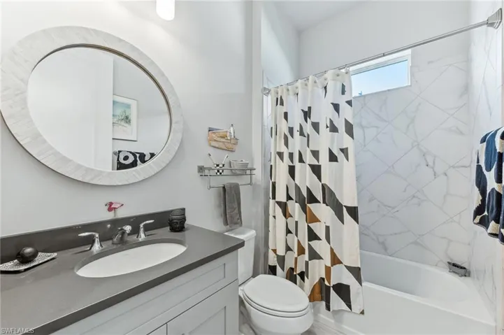 Bathroom with shower / bathtub combination with curtain, toilet, and vanity