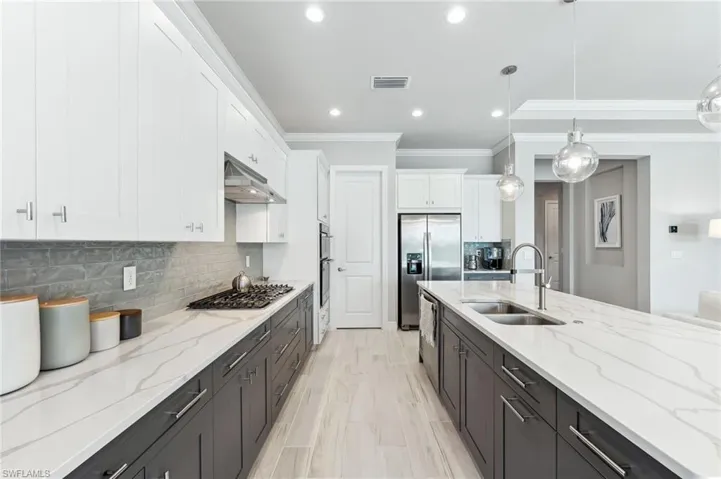 Kitchen featuring visible vents, under cabinet range hood, appliances with stainless steel finishes, white cabinets, and a sink