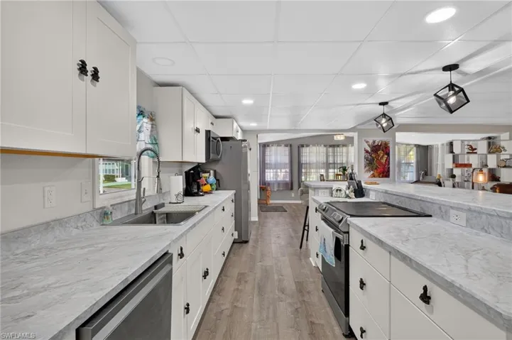 Kitchen featuring white cabinetry, light-toned countertops, wood-finish flooring, recessed lighting, and modern pendant fixtures