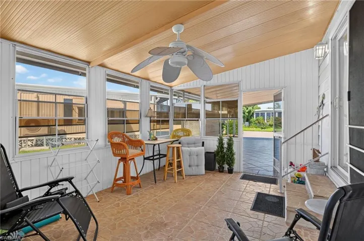 Enclosed porch featuring a light wood-finish ceiling, ceiling fan, multiple windows, and a tiled floor