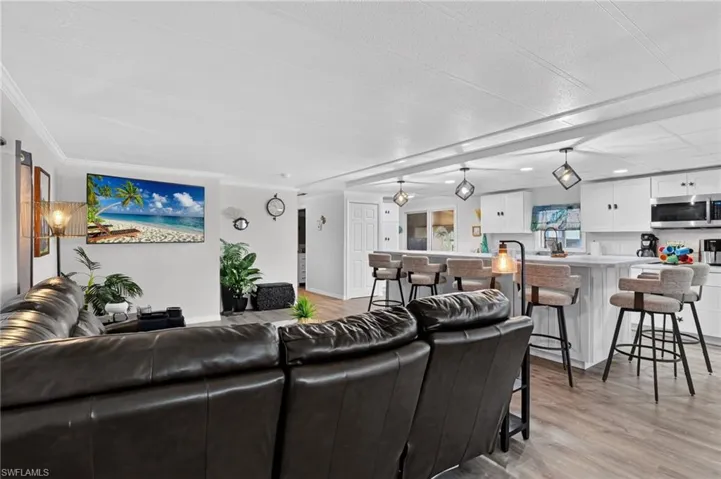 Open-concept living space featuring wood-finish flooring, white walls, and crown molding