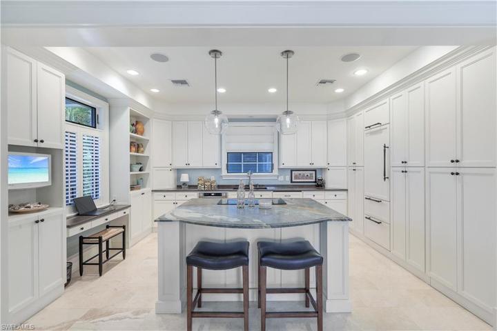 Bright, open air kitchen features onyx island w/ breakfast bar, computer deck overlooking front walkway, display shelves, window sink, paneled Sub Zero refrigerator w/ freezer drawers plus hidden paneled pantry and marble flooring!