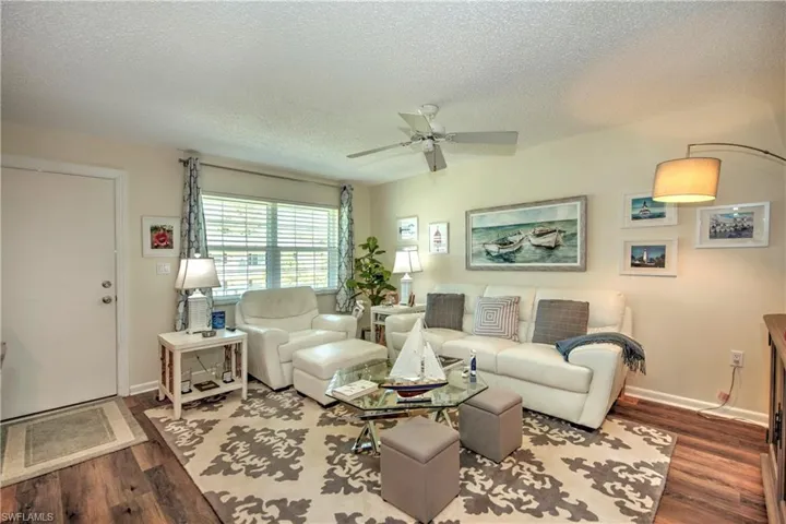 Living room with wood-type flooring, ceiling fan, and a textured ceiling