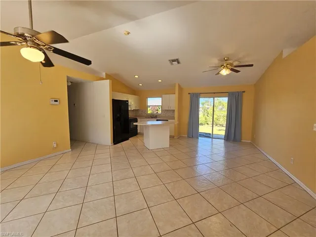 Unfurnished living room with light tile patterned floors, vaulted ceiling, sink, and ceiling fan