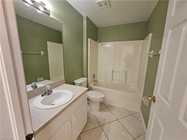 Full bathroom featuring toilet, vanity, bathtub / shower combination, and tile patterned floors