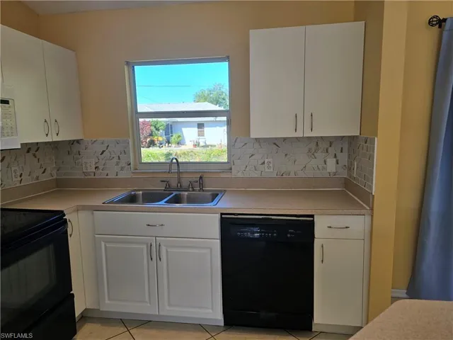 Kitchen with decorative backsplash, dishwashing machine, white cabinetry, range, and sink