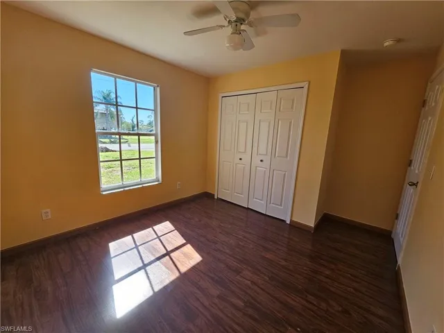 Unfurnished bedroom with ceiling fan, a closet, and dark hardwood / wood-style floors