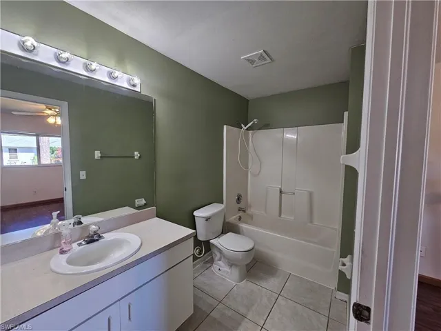 Full bathroom with bathtub / shower combination, tile patterned flooring, vanity, ceiling fan, and toilet